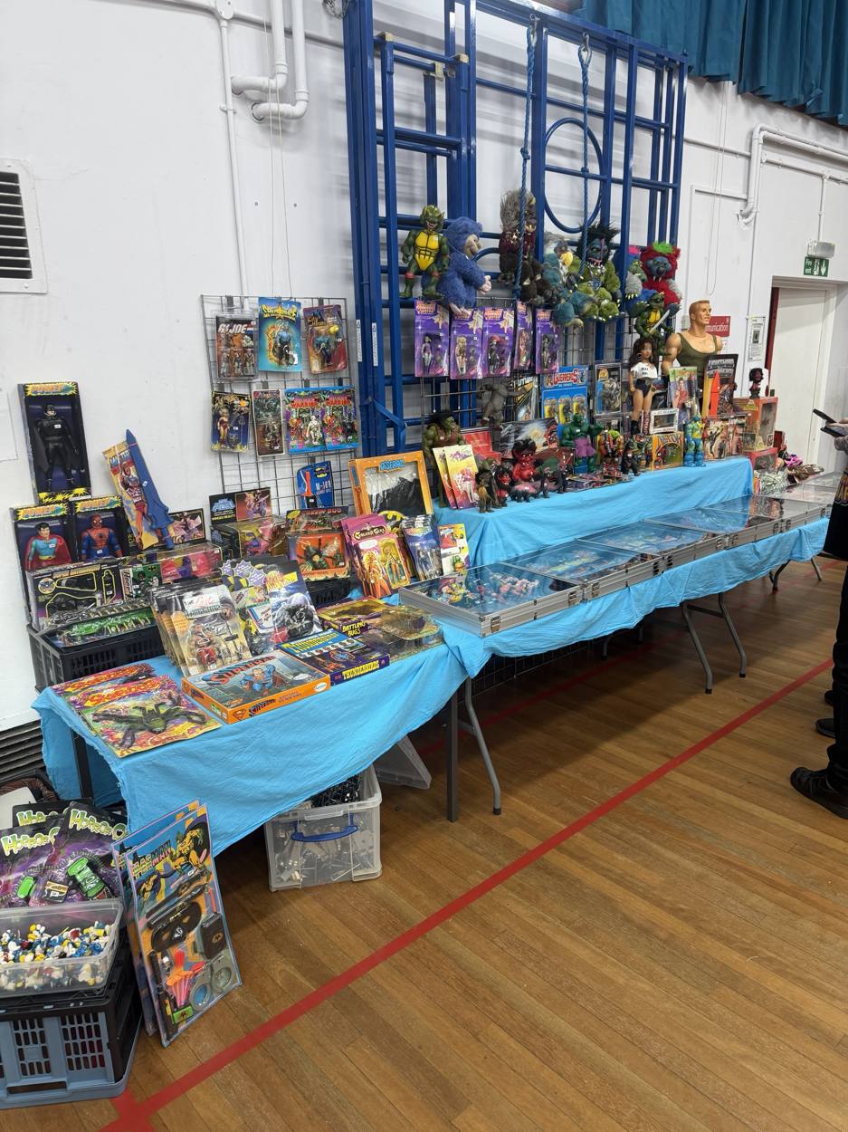 Wall of carded 80s and 90s action figures above a blue table
