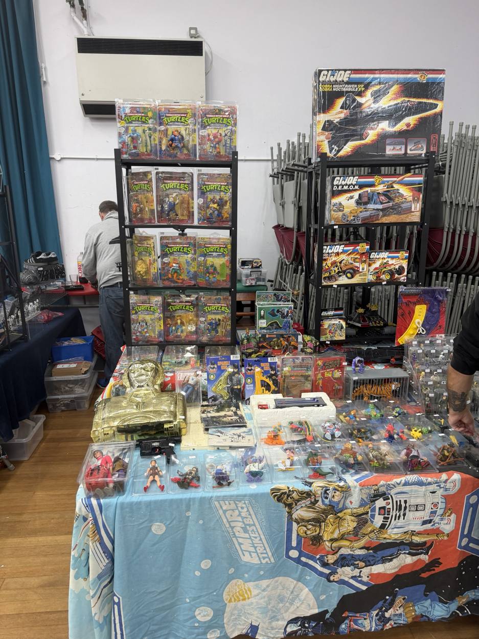 Carded Teenage Mutant Ninja Turtles figures and boxed G.I. Joe vehicles on a trader's table