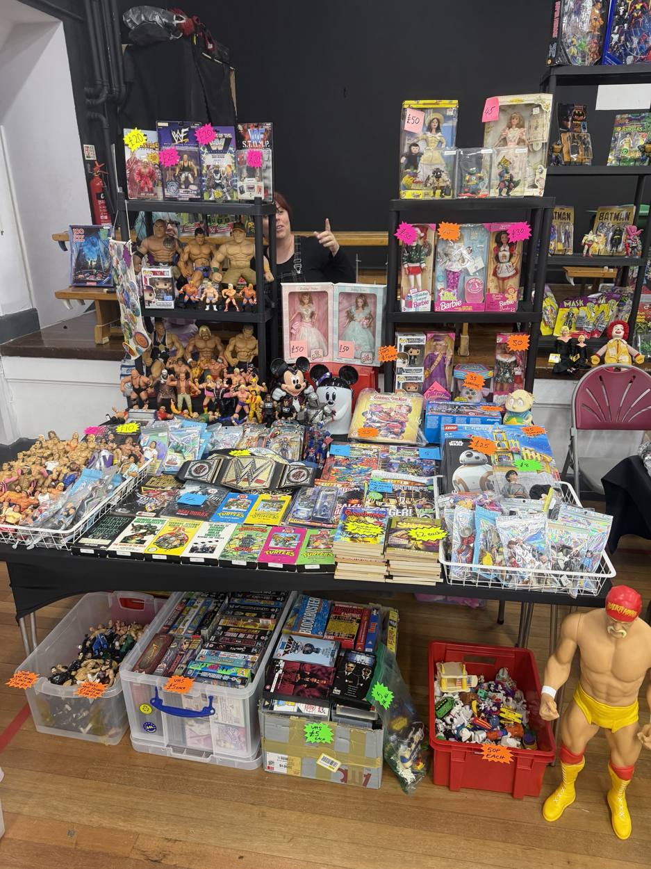 Trader's table of vintage wrestling figures, boxed Barbies, Turtles VHS tapes and Goosebumps books